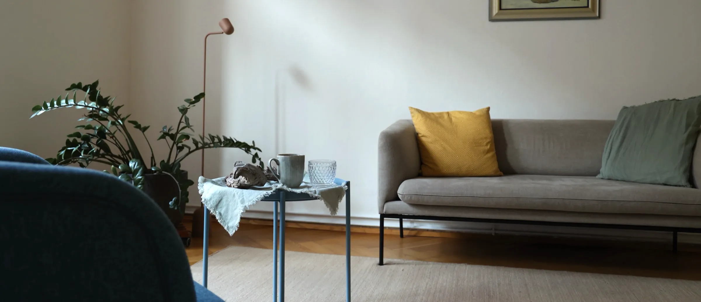 Die Praxis in Graz: Sofa mit Kissen, Pflanze und ein kleiner Tisch